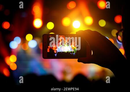 Man takes a picture of the show at the concert hall using a smartphone. Stock Photo