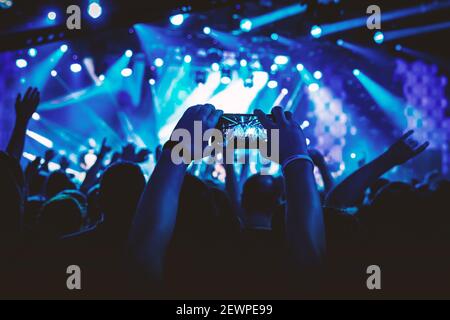 Man takes a picture of the show at the concert hall using a smartphone. Stock Photo