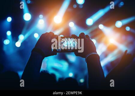 Man takes a picture of the show at the concert hall using a smartphone. Stock Photo