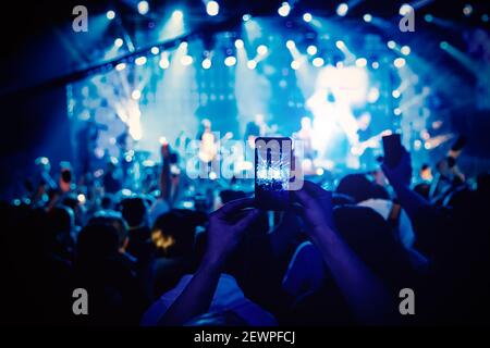Man takes a picture of the show at the concert hall using a smartphone. Stock Photo