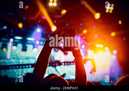Man takes a picture of the show at the concert hall using a smartphone. Stock Photo