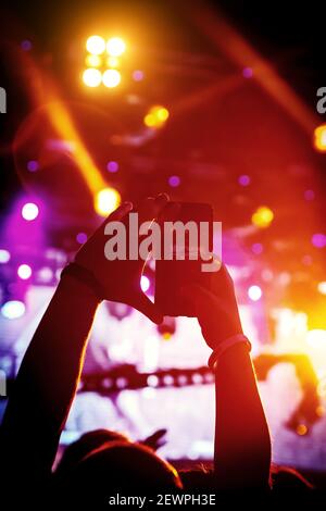 Man takes a picture of the show at the concert hall using a smartphone. Stock Photo