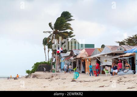 Punta Cana, Dominican republic - January 14, 2020: Tourists walk on a sandy beach of Punta Cana resort near small souvenir shops and beach restaurants Stock Photo