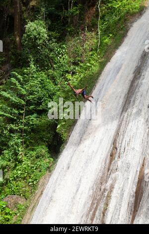 Samana, Dominican republic - January 7, 2020: Local young man jumps from the top of waterfall in tropical forest. Samana district Stock Photo