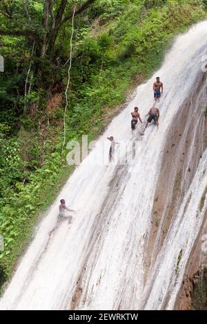 Samana, Dominican republic - January 7, 2020: Local young men climb the waterfall in tropical forest for jumping from top. Samana district Stock Photo