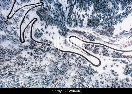 Aerial view of Maloja Pass mountain road crossing the winter forest covered with snow, Canton of Graubunden, Switzerland, Europe Stock Photo