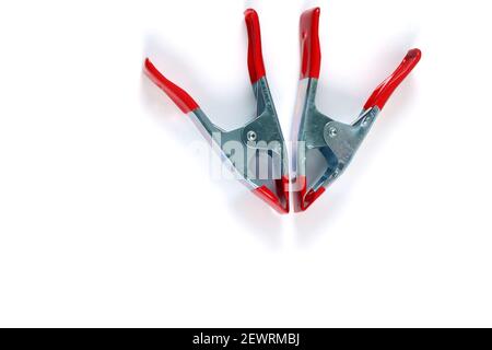The metal spring clamps with red plastic handles and tip isolated on white background Stock Photo