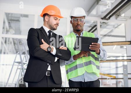 Multiethnic men using tablet for work on construction project Stock Photo