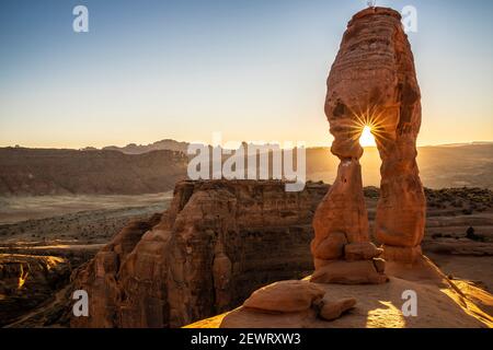 Setting sun through Delicate Arch with sunburst, Arches National Park, Utah, United States of America, North America Stock Photo