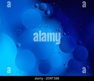 A close up of oil droplets on water lit with coloured light Stock Photo