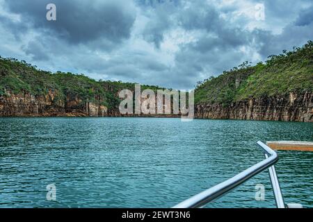 Navigating in a boat on a river next to canyons on a cloudy day. Bad weather. Stock Photo