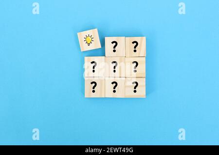 Concept of problem solving, creativity, idea or innovation. Male hand places a wooden cube with hand drawn light bulb next to the cubes with question Stock Photo