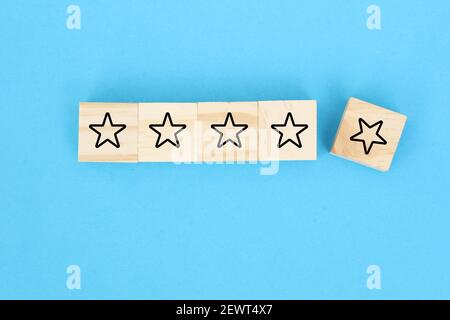 Male hand placing wooden cubes with five star rating on yellow background. Customer experience or satisfaction survey concept. Stock Photo