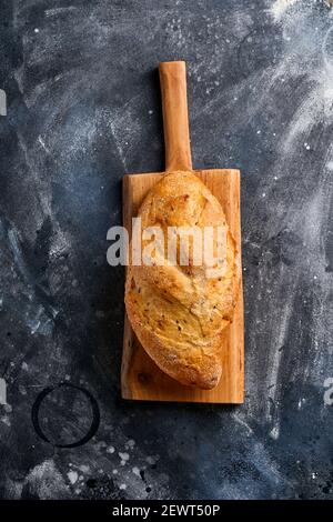 Homemade bread with seeds on a wooden stand, wheat flour and ears on gray old concrete background table. Top view flat lay with copy space Stock Photo