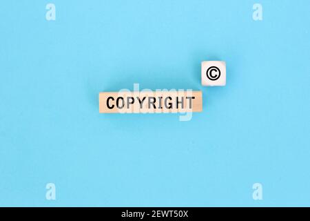The word copyright and copyright symbol on wooden blocks on Blue background. Concept of patenting or copyright protection. Stock Photo