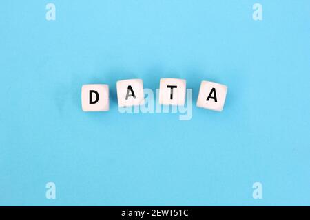 The word data on wooden cubes against pile of files and folders background. Data collection for research or business investment decisions concept. Stock Photo