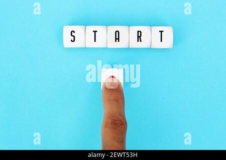 The word start on cubes with a male hand pressing the start button. To make a new start in life, business, education or career concept. Stock Photo