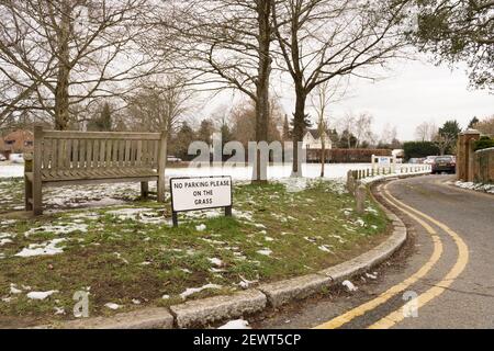 wooden bench in snow covered green in winter, 'no parking please in the grass' sign, Kent, Bessels green Stock Photo