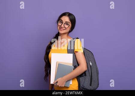 Happy indian female student wearing eyeglasses holding notebooks Stock Photo