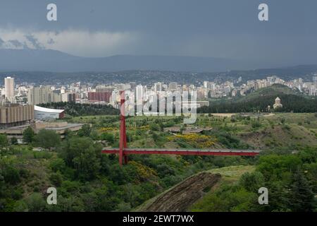 Gorgeous panoramic view of Tbilisi, Georgia under the approaching rain storm, with pedestrian footbridge over the ravine dominating the shot Stock Photo