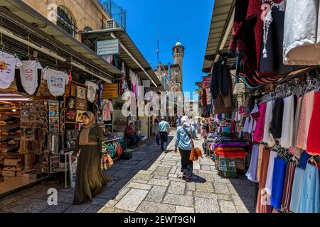 People walking on narrow street among typical arab shops on famous bazaar located in Old City of Jerusalem, Israel. Stock Photo