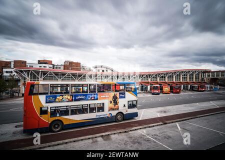 New modern bus station in centre of village with dramatic storm sky above, double single decker busses picking up shoppers and commuters for journey Stock Photo