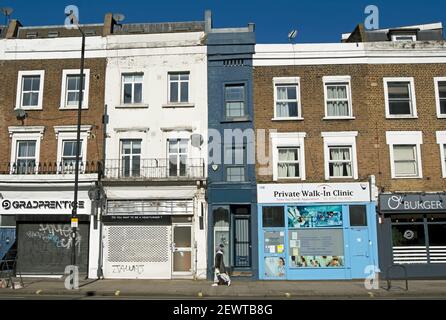 with dark-painted exterior, what is said to be the narrowest house in london seen with a passing female pedestrian, shepherds bush, london, england Stock Photo