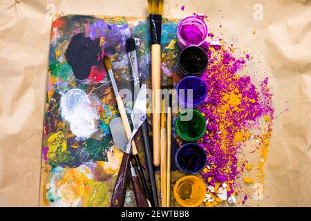 Painting tools arranged in the most artistic way. Jars with watercolor, brushes and color palette on the painter's table Stock Photo