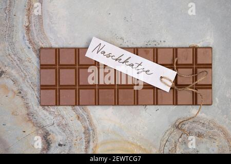 delicious whole chocolate bar lies on light stone background with a small label that says naschkatze Stock Photo
