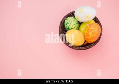 Colored Easter eggs with beautiful patterns arranged in a basket and isolated in the pink background with a copy space from the left Stock Photo