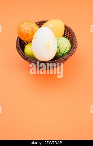 A basket with colorful Easter eggs isolated in the bright orange background Stock Photo