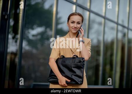 Urban realtor walking in the city using her mobile phone. Business Woman Uses Smartphone Stock Photo