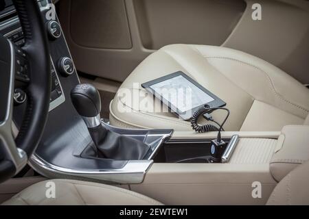 E-Book Reader on the passenger seat of a car, plugged in USB socket Stock Photo