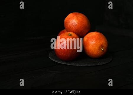 Whole and halved red oranges on black surface. Stock Photo