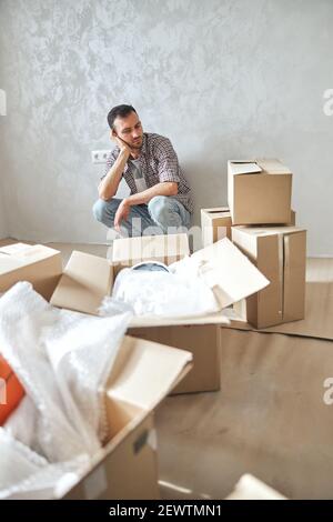 Low-spirited young man sitting in his new flat Stock Photo