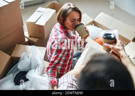 Couple with disposable paper cups seated on the floor Stock Photo