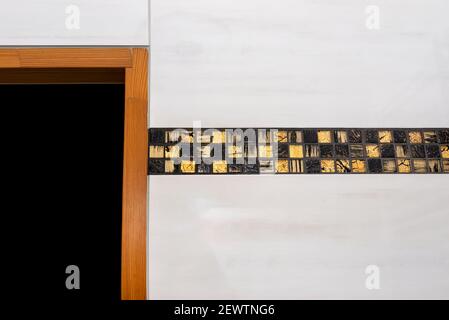 The room in the house is lined with classic ceramic tiles with a golden mosaic, visible wooden door frame. Stock Photo