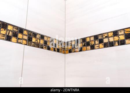 The room in the house is lined with classic ceramic tiles with a golden mosaic, tiles meet in the corner of the room. Stock Photo
