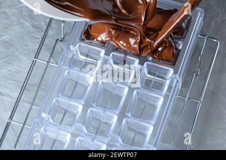 Confectioner placing the tempered chocolate in a polycarbonate form. Stock Photo