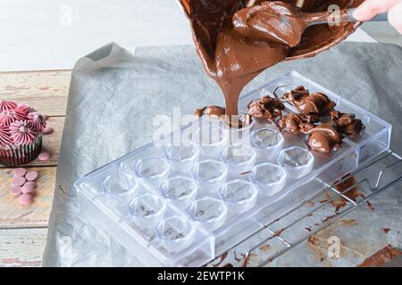 Closeup of confectioner pouring tempered chocolate in a polycarbonate form. Stock Photo