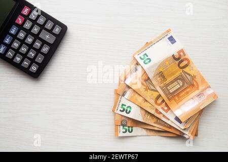 Euro cash banknotes and calculator on white table Stock Photo