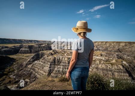 Female traveler looking at view at Horseshoe Canyon near Drumheller in Alberta, Canada. Stock Photo