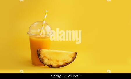 Pineapple juice in a plastic cup on yellow background Stock Photo