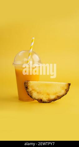 Pineapple juice in a plastic cup on yellow background Stock Photo