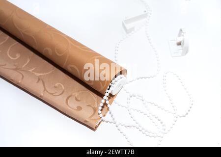 Beige textile roller blinds with manual adjustment mechanism on a white background. Home improvement. Stock Photo