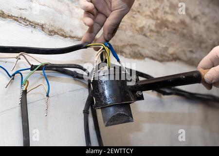 An electrician solders twisted electrical wires in a house under construction. Connection and twisting of cables. Stock Photo