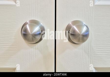 White wooden cupboard doors with silver doorknobs, closeup selective focus. Color swatch sample with copy space. Stock Photo