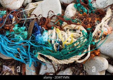 The remnants of fishing nets and ropes washed up on a pebble shoreline in West Cork, Ireland. Marine debris and litter is becoming a major problem.