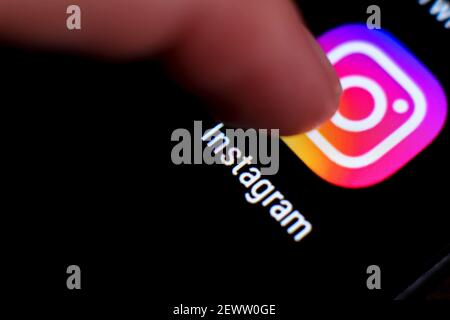 Madrid, Spain- March 3, 2021: Finger pressing Instagram icon on black mobile phone screen. Stock Photo