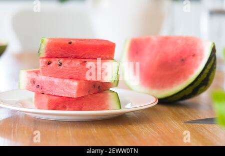 Ripe cut slices of watermelon on a plate, sliced watermelons on a table in a UK kitchen or dining room Stock Photo